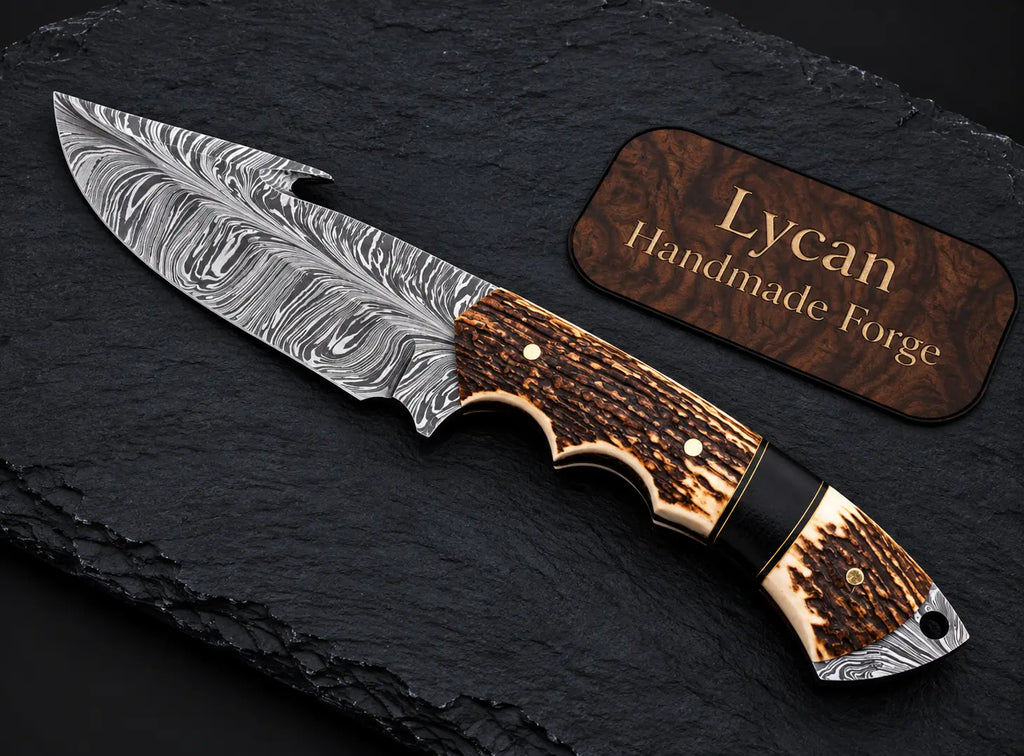 Damascus skinner knife with gut hook on slate background - full length view
