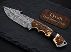 Damascus skinner knife with gut hook on slate background - full length view