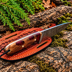 Damascus skinner knife on wood background - side angle